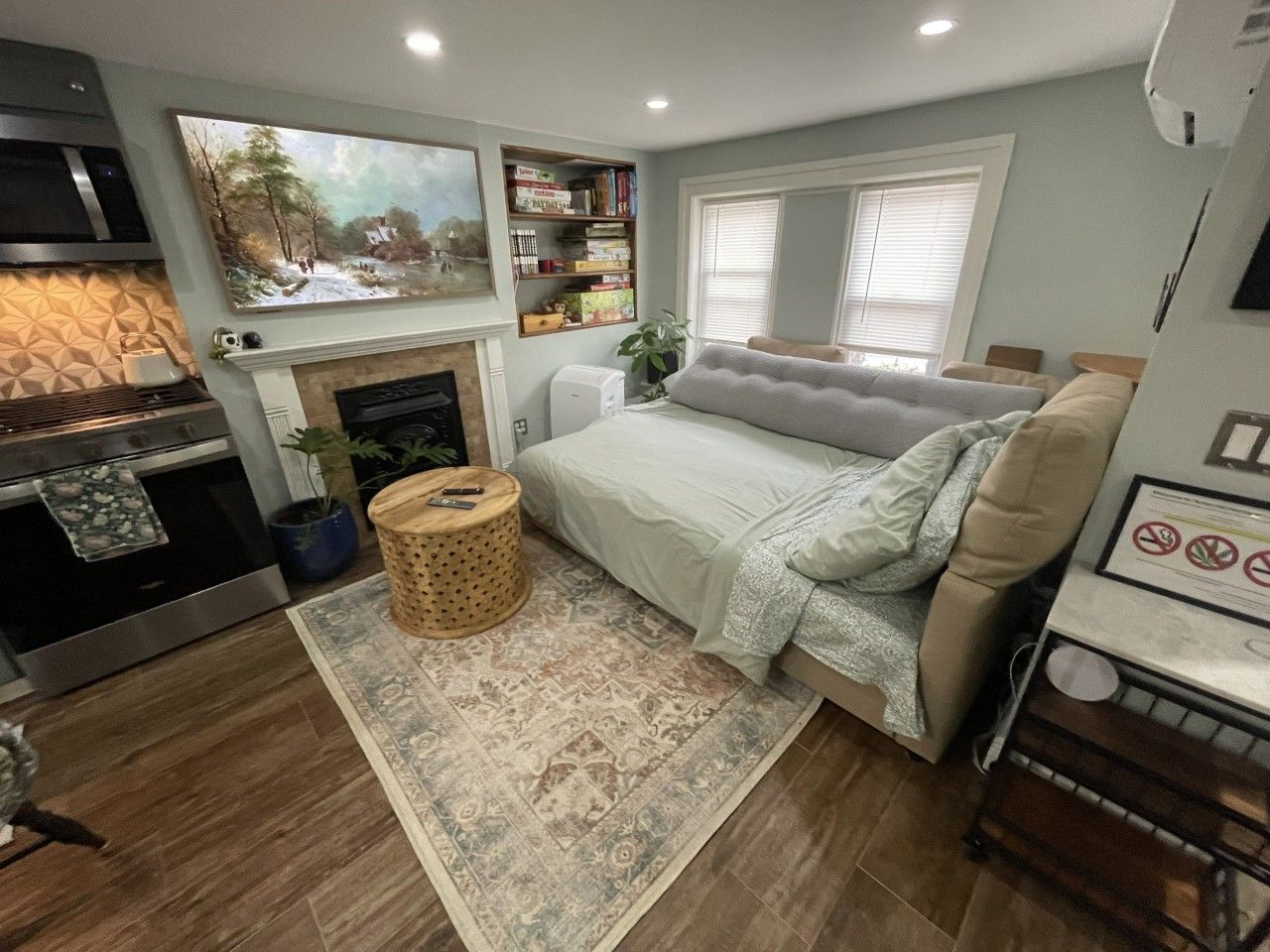 A cozy living room with a fireplace, a sofa, a dining table, and a bookshelf.
