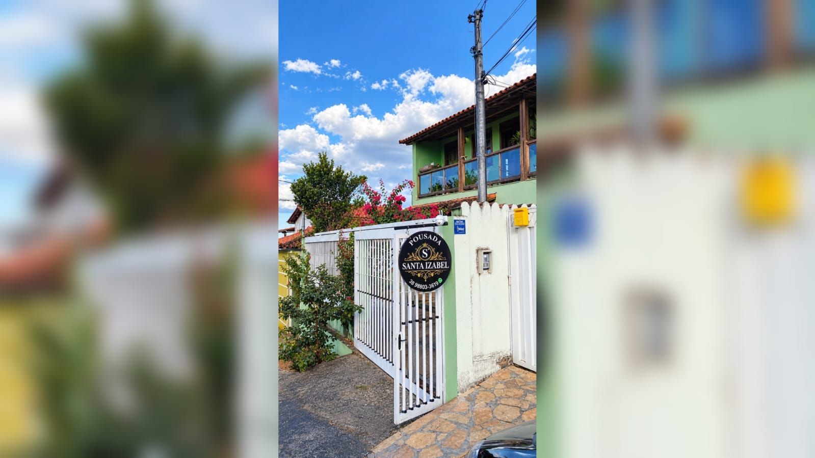 Una entrada tancada amb un senyal, un edifici amb façana verda i un cel serè.