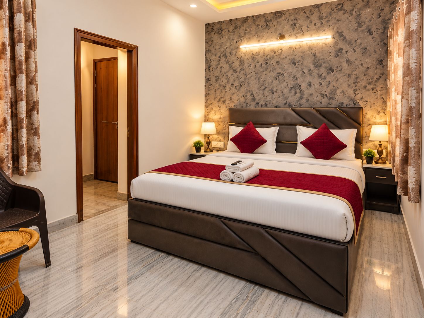 Une chambre d’hôtel avec un grand lit, une porte en bois, un mur orné d’un motif floral et une table de chevet avec une lampe.