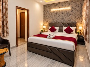 Ein Hotelzimmer mit einem großen Bett, einer Holztür, einer Wand mit floralem Muster und einem Nachttisch mit einer Lampe.