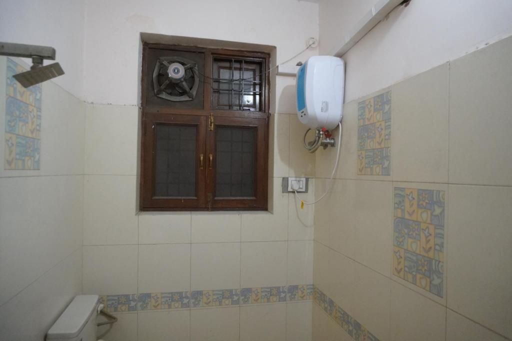 Une salle de bain équipée d’un ventilateur, d’un sèche-mains et d’une fenêtre à croisillons.