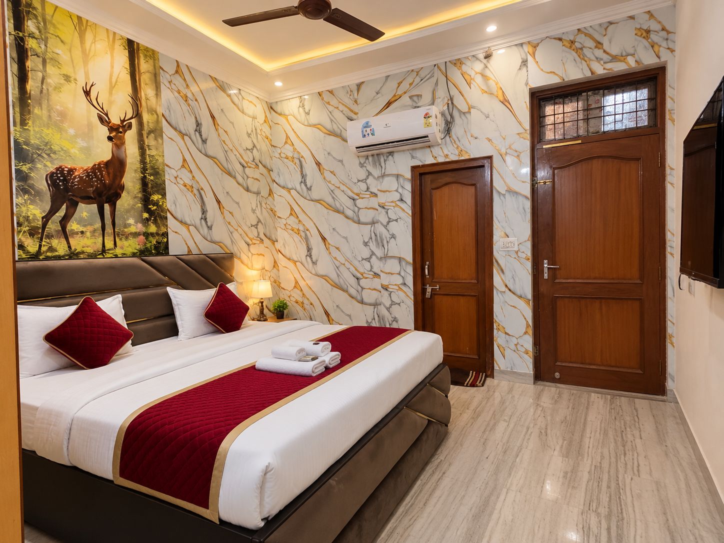 Habitación de hotel con cama, ventilador de techo, aire acondicionado, puerta de madera y pared con diseño de mármol.
