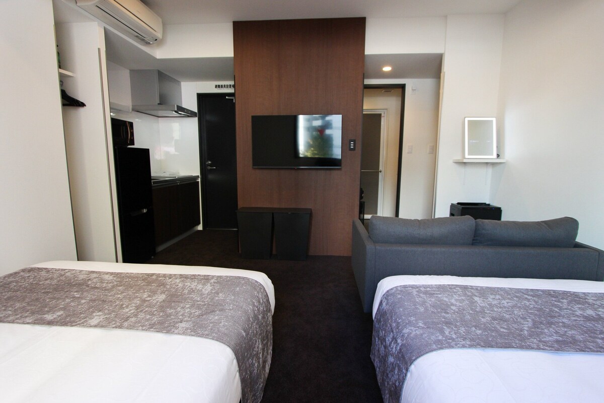 Une chambre d’hôtel avec deux lits, une télévision, un coin cuisine et un canapé.