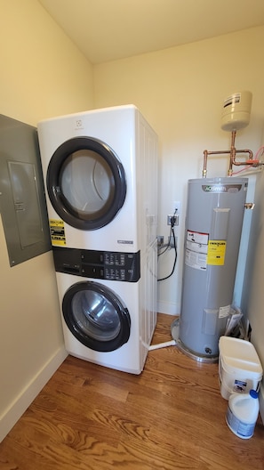 Ein kleiner Hauswirtschaftsraum mit einer Waschmaschine und einem Trockner, einem Warmwasserbereiter und einer Wasserfilteranlage.