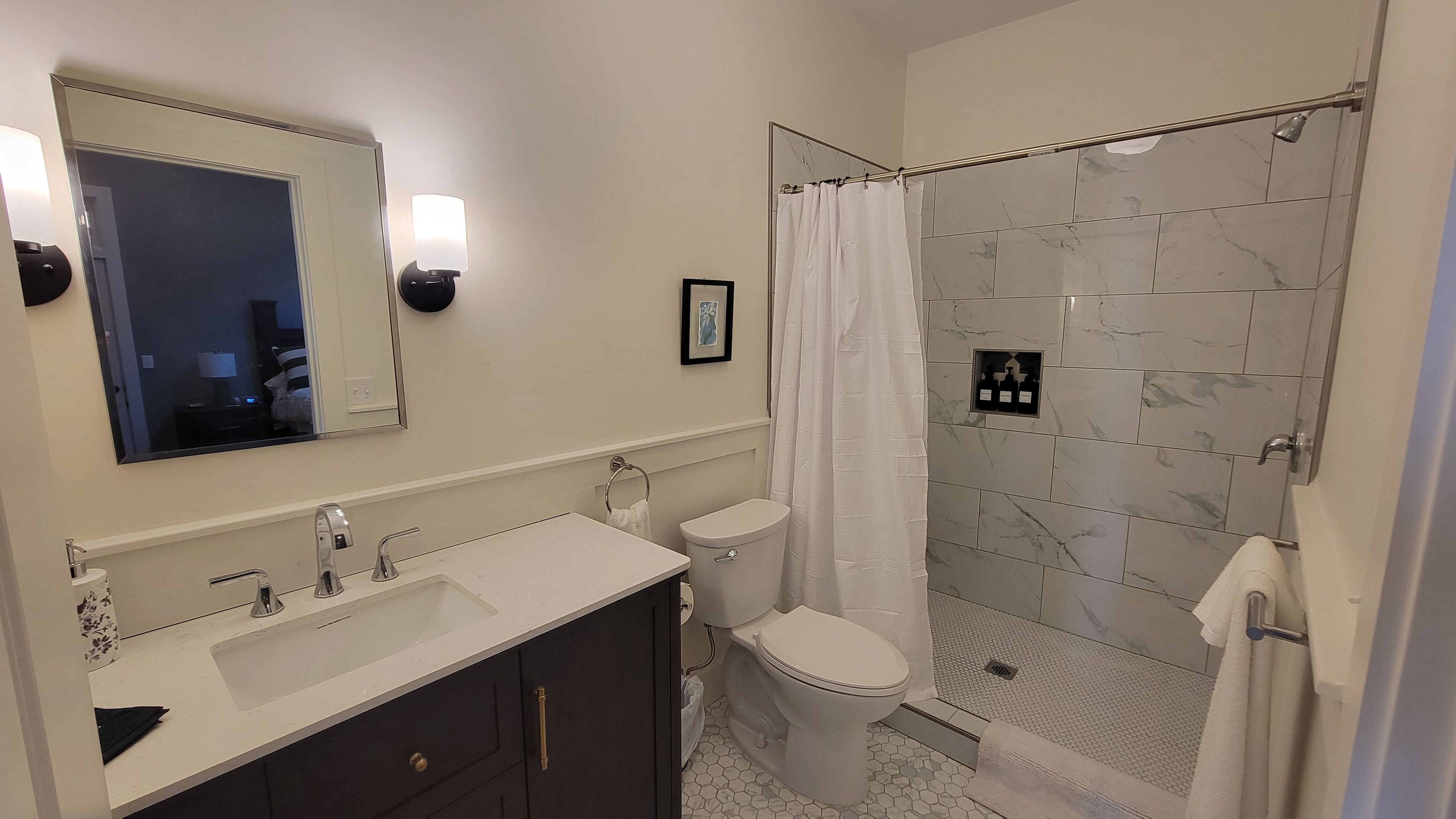 A modern bathroom with a double sink vanity, a toilet, and a glass-enclosed shower area.