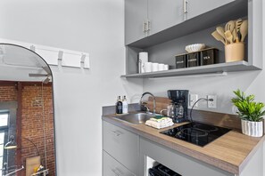 Een moderne keuken met een inbouwvaatwasser, een koffiezetapparaat en een plant op het aanrecht.