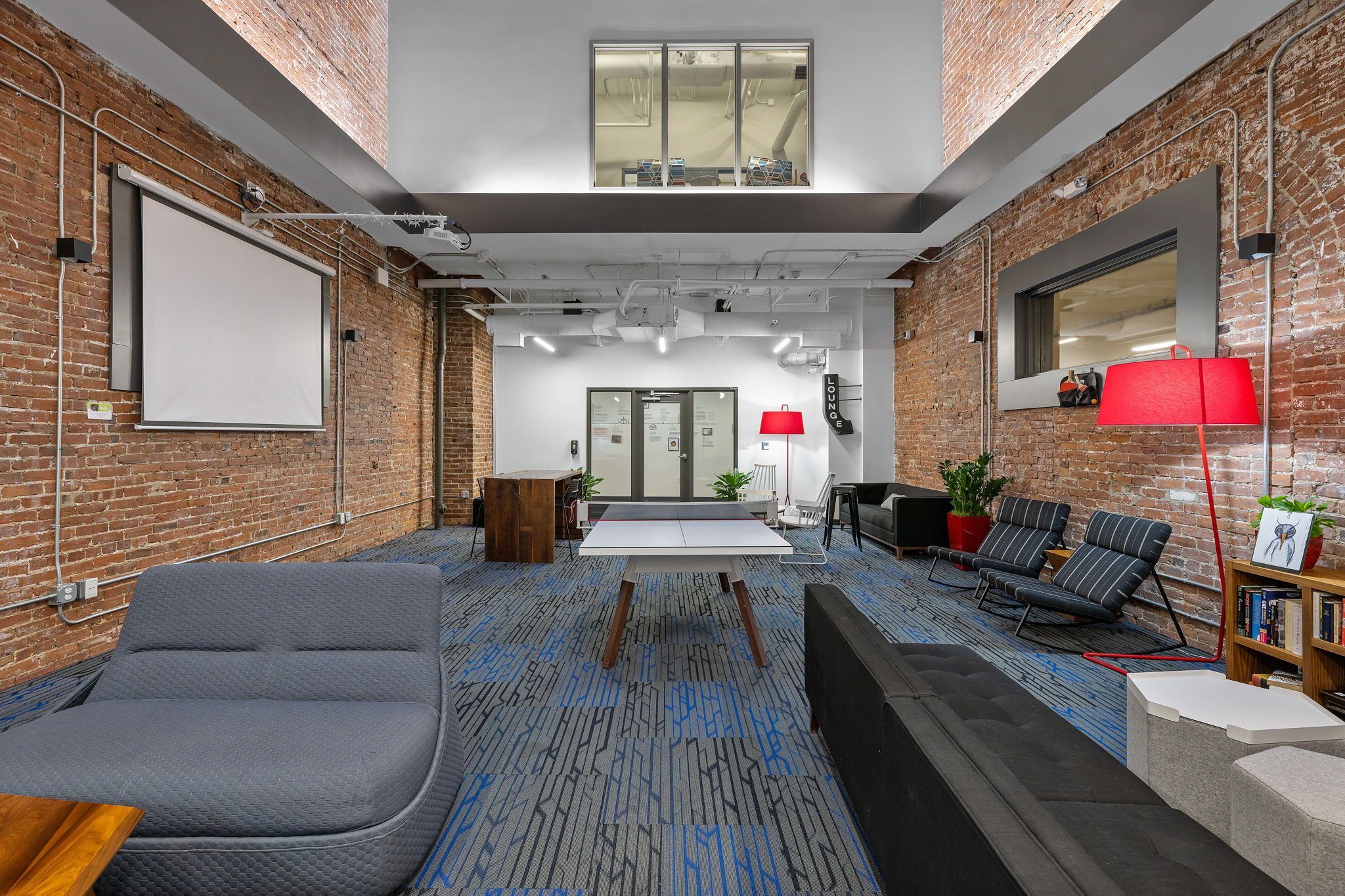 A modern office space with a large screen, seating area, and a red lamp.