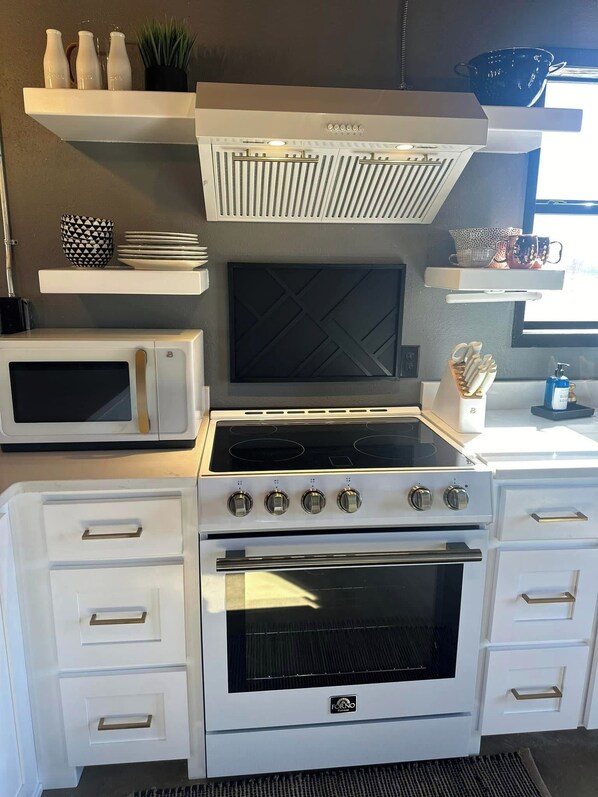 A kitchen with a stove, oven, microwave, and white cabinetry. - Cozy 2-bedroom house in Idabel, OK only 10 miles to Broken Bow, OK (Idabel)