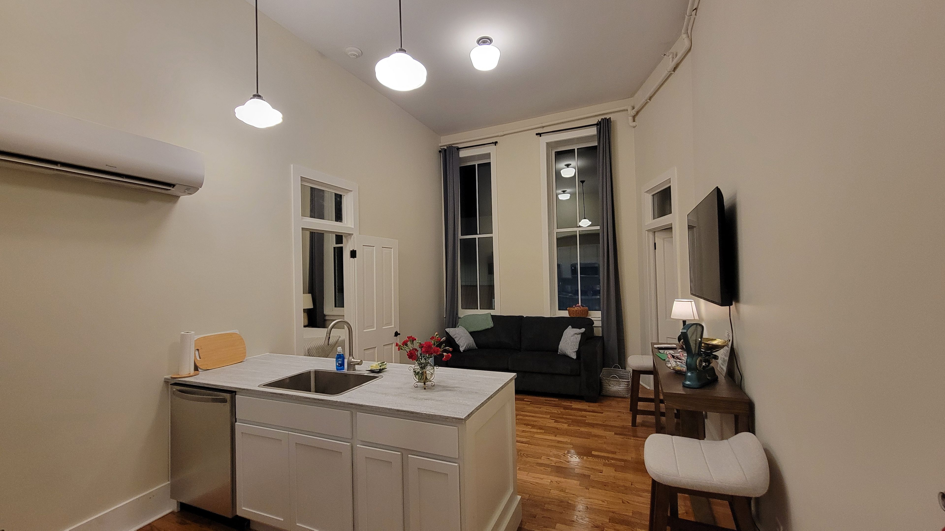 Un espace de vie compact comprenant un coin cuisine, un coin repas et un coin salon avec un canapé et un téléviseur.
