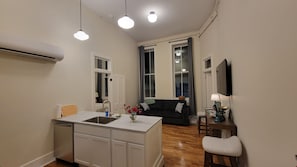 Un espace de vie compact comprenant un coin cuisine, un coin repas et un coin salon avec un canapé et un téléviseur.