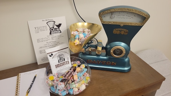 A vintage Dayton scale, a bowl of assorted candies, a handwritten note, and a box of Horehound Hall candies on a wooden table.