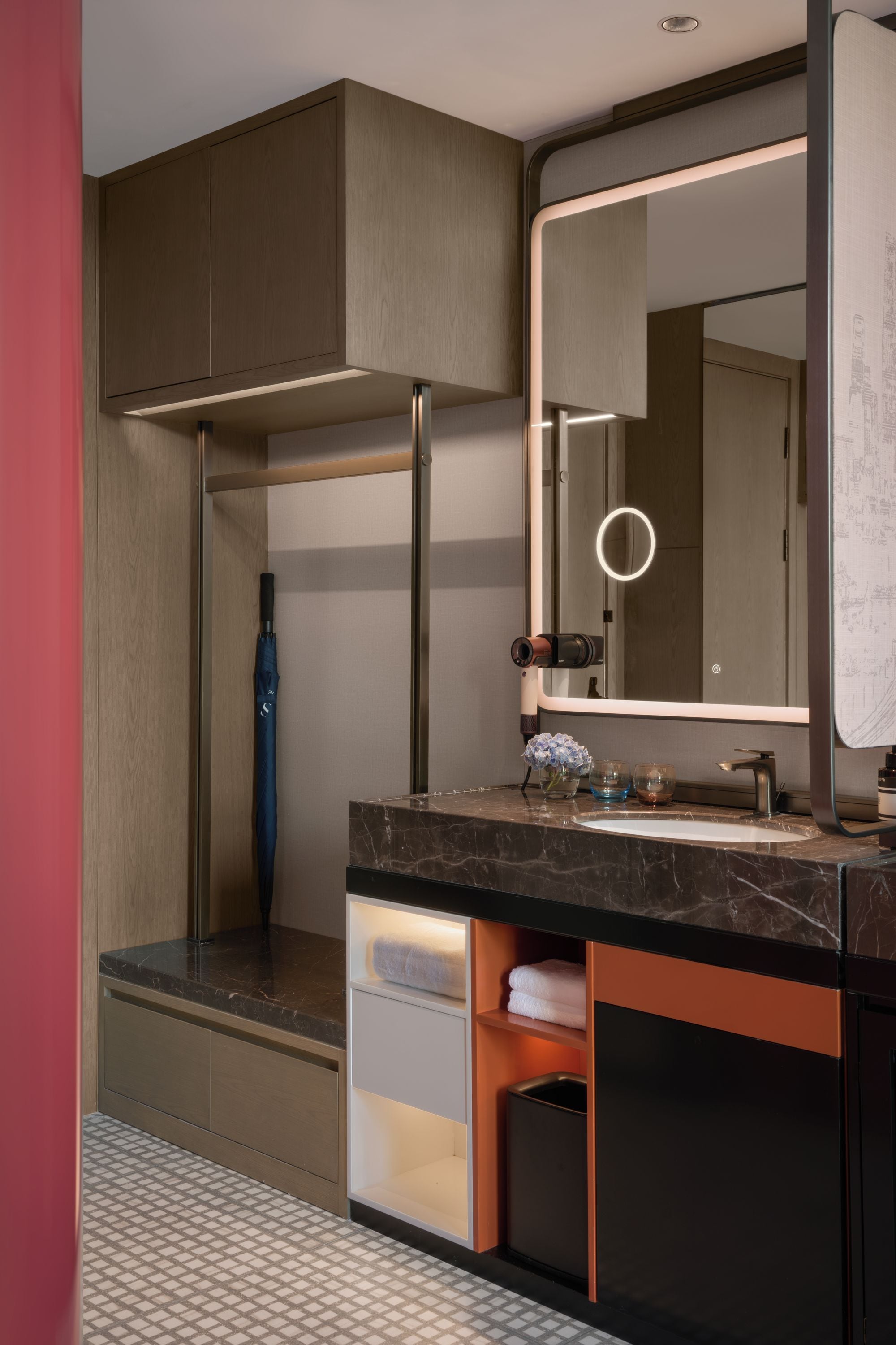 Un baño moderno con encimera de mármol, un espejo grande y un perchero.