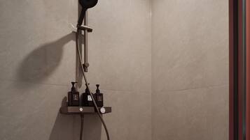 Ducha moderna con cabezal de ducha de mano y mandos en un panel fijado a la pared.