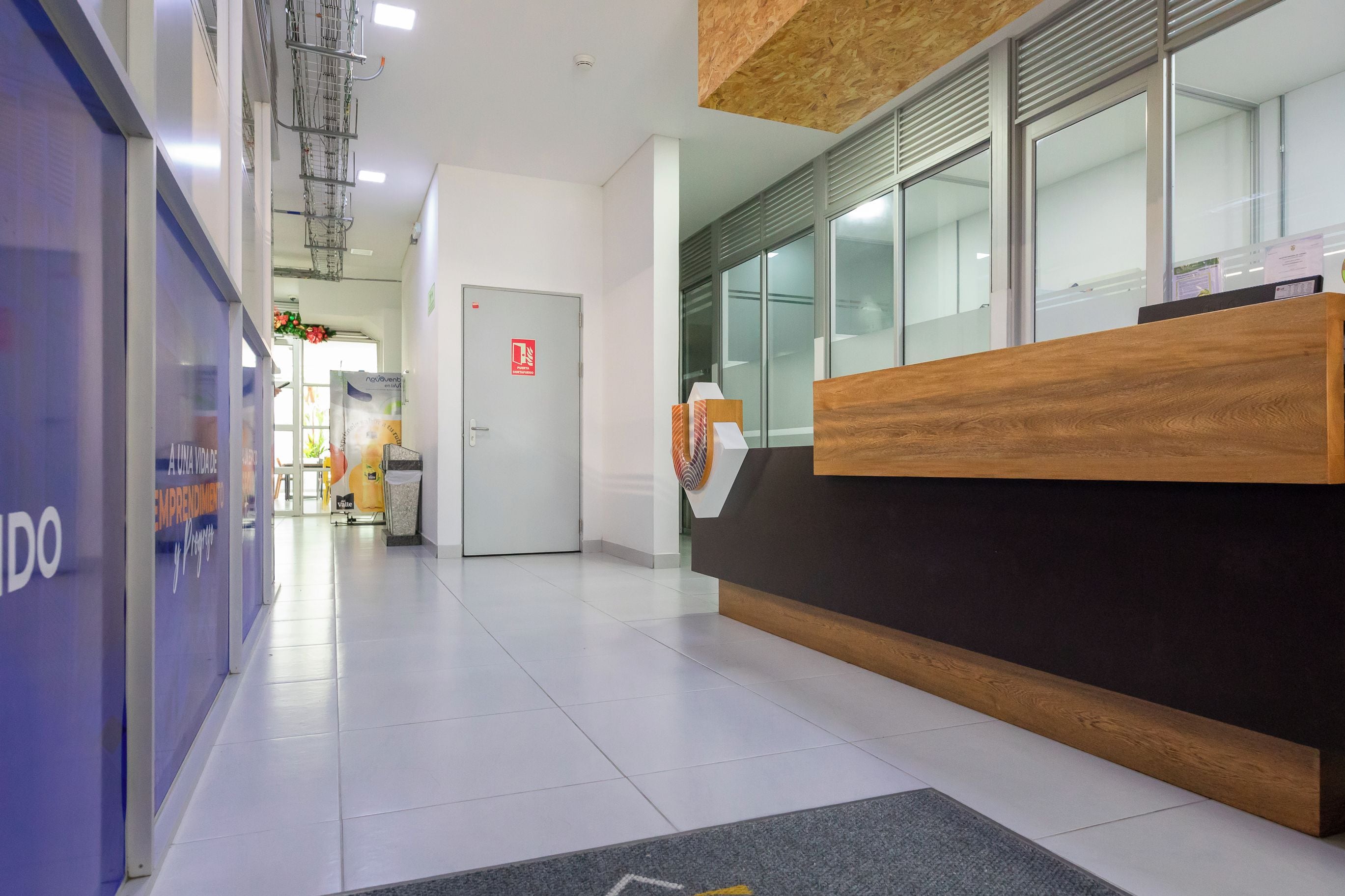 Una zona de recepción con un mostrador de madera, un muro de cristal y suelo de baldosas.