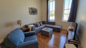 A modern living room with a sectional sofa, a small table, and a lamp.