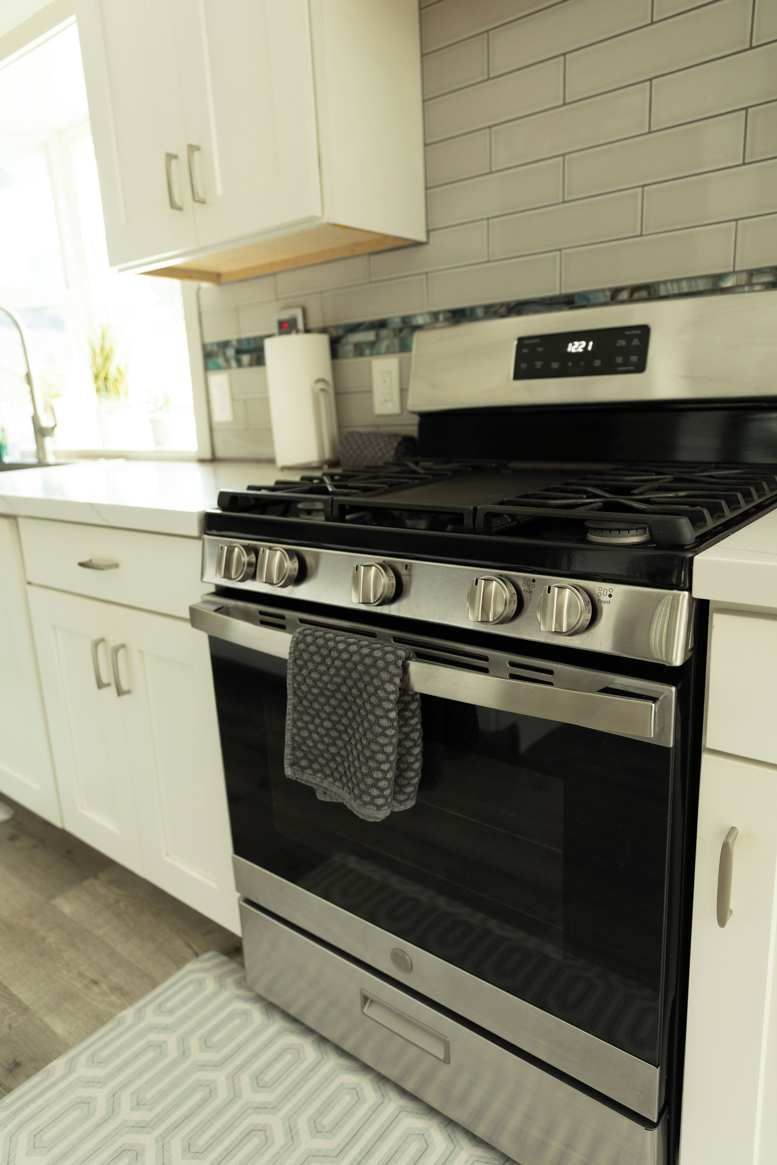Une cuisine équipée d’une cuisinière, d’un four et d’armoires blanches, le tout en acier inoxydable.