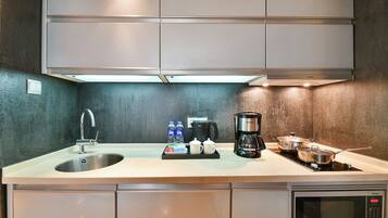 Una cocina moderna con un lavamanos de acero inoxidable, una cafetera Siemens y un microondas.