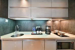 Una cocina moderna con un lavamanos de acero inoxidable, una cafetera Siemens y un microondas.