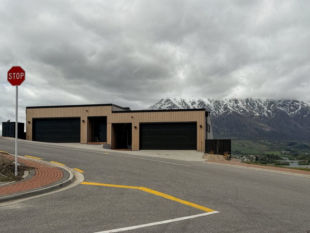 A building with two garage doors, a stop sign, and a mountainous landscape in the background.