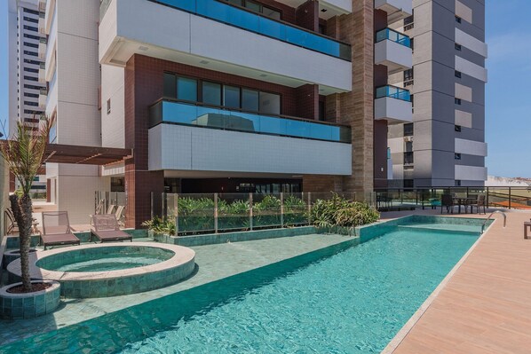 A modern hotel with a swimming pool, outdoor seating, and a view of the surrounding buildings. - Pier 430 - Near the Beachfront With Pool, Panoramic Rooftop, Gym, Coworking and Complete Leisure Facilities by Carpediem (Fortaleza)
