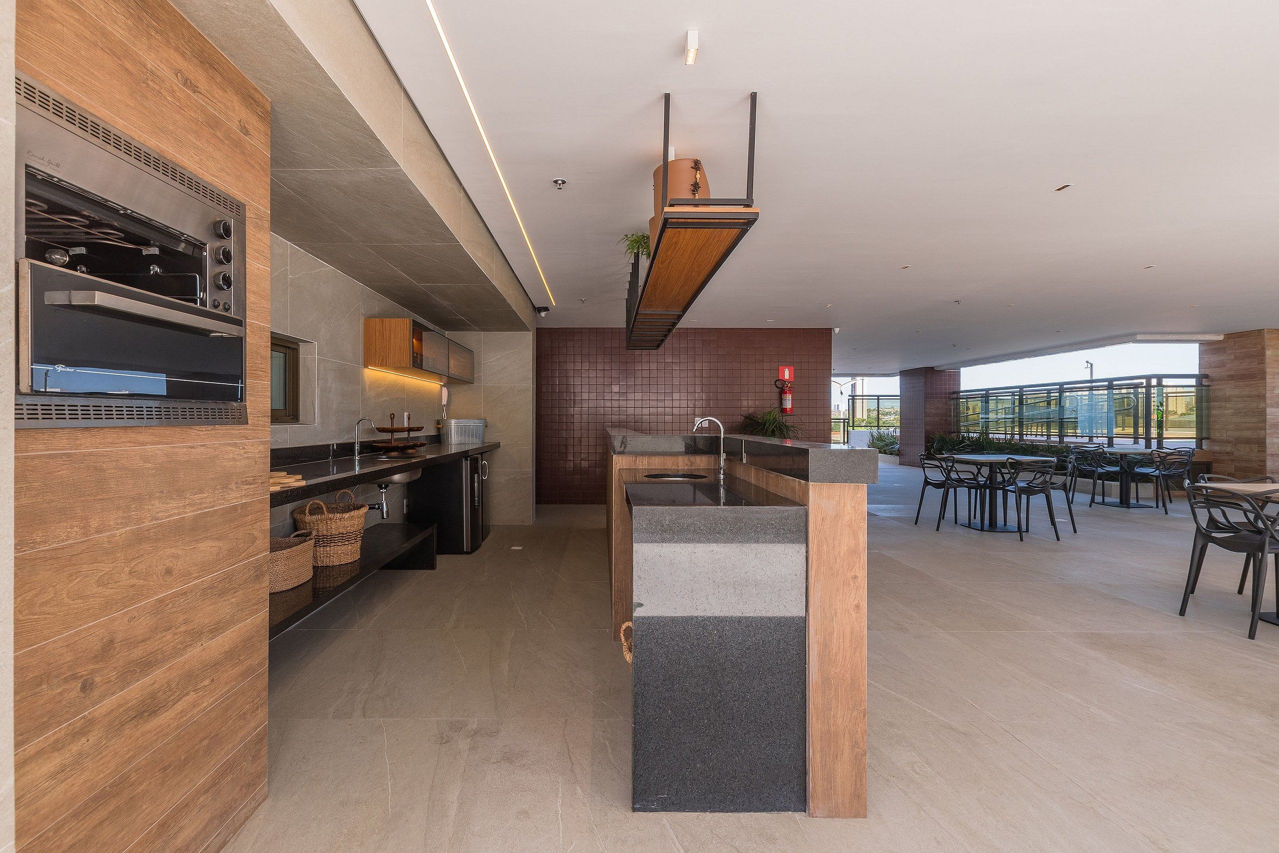 Una cocina moderna con una parrilla integrada, una isla central con un lavamanos y un comedor con asientos exteriores.