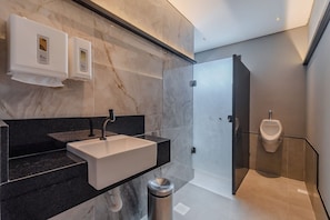 A modern bathroom with a marble wall, a sink, and a urinal. - Pier 430 - Near the Beachfront With Pool, Panoramic Rooftop, Gym, Coworking and Complete Leisure Facilities by Carpediem (Fortaleza)