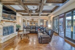 A spacious living area with a fireplace, leather sofa, and a large window overlooking a pool.
