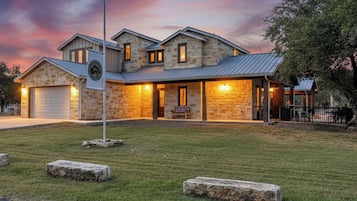 A two-story stone house with a metal roof, a garage, and a well-maintained lawn.
