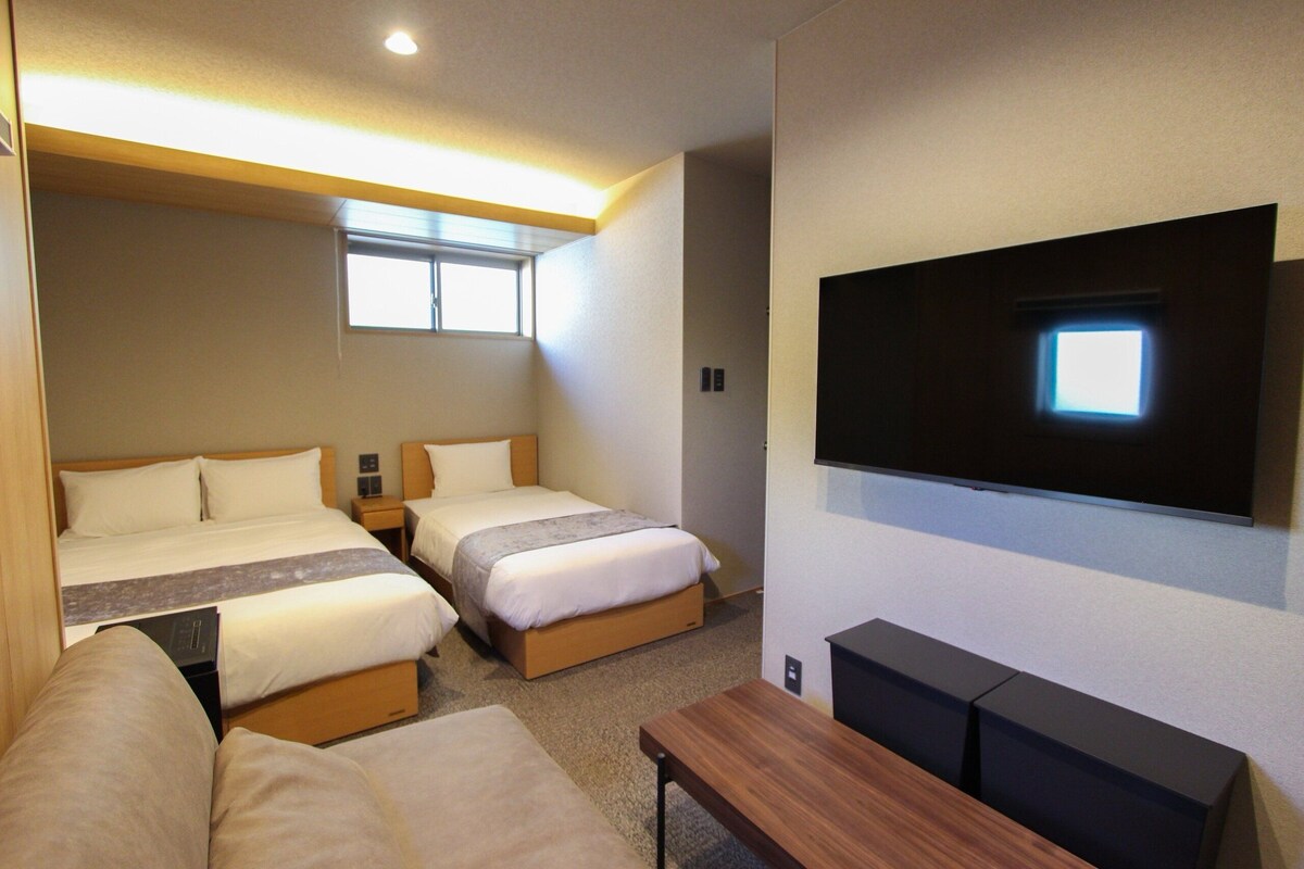 A hotel room with two beds, a TV, and a seating area.