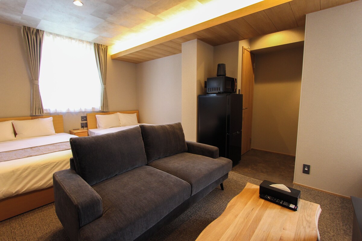 A hotel room with a bed, a sofa, a desk, and a microwave on a cabinet.