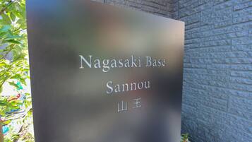 Un letrero con el texto 'Nagasaki Base Sannou' y un símbolo.