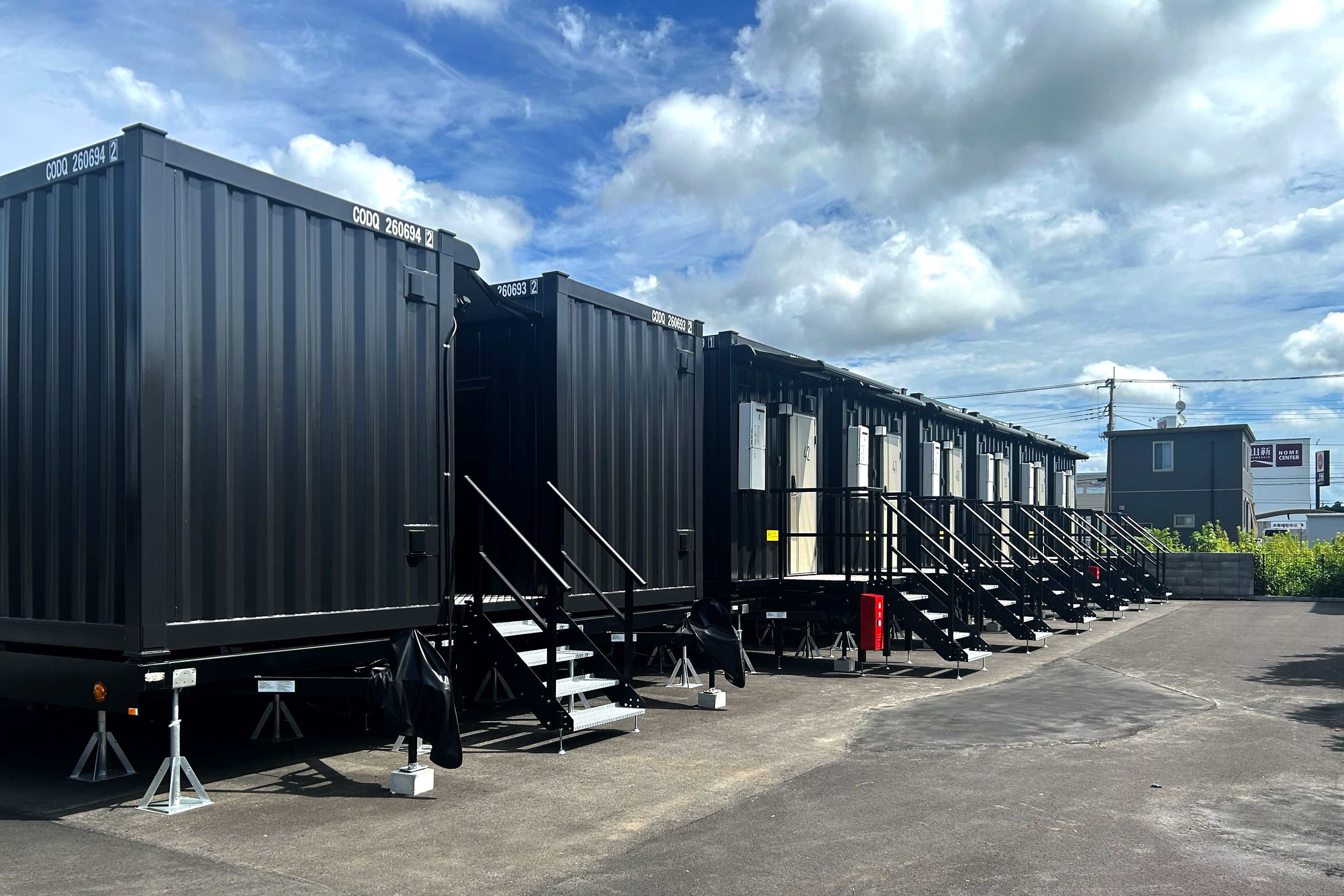 A row of large shipping containers arranged in a parking lot.