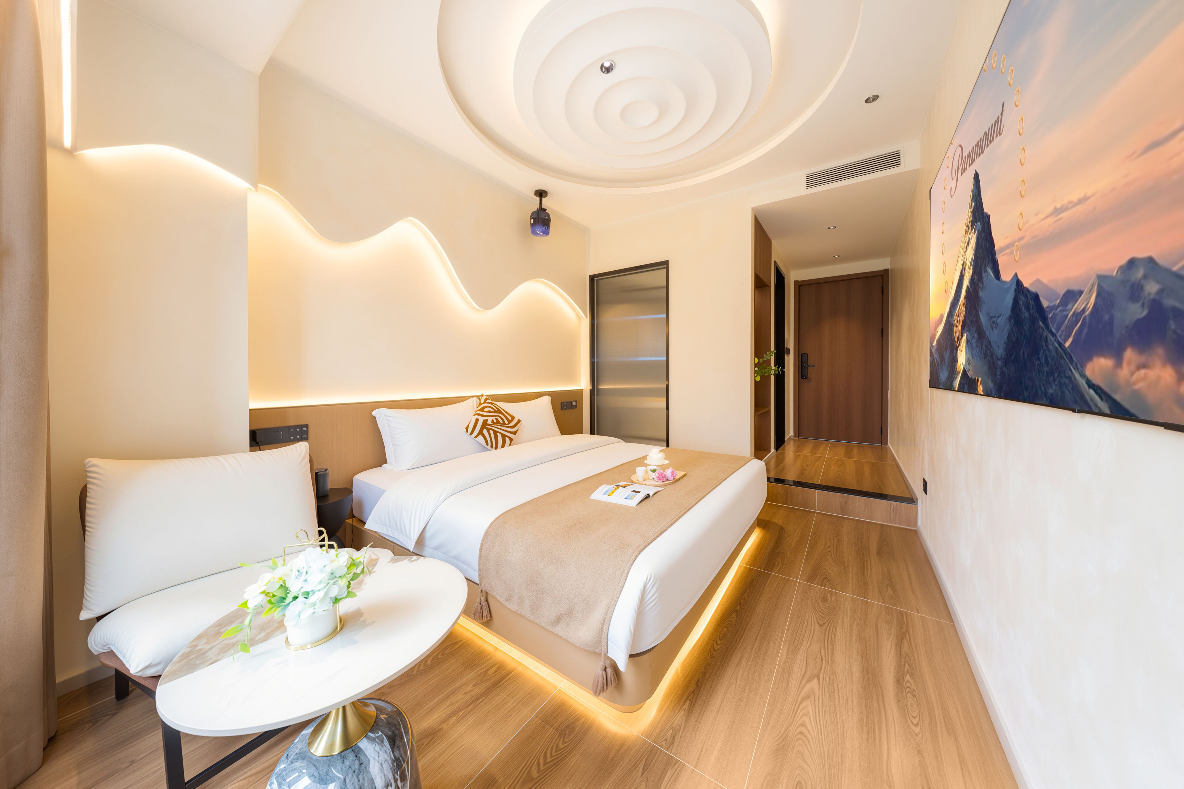Une chambre d’hôtel moderne avec un lit, une table de chevet et un tableau au mur.