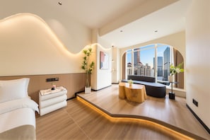Habitación de hotel moderna con techo curvo, un sofá, una mesita y vistas a la ciudad.