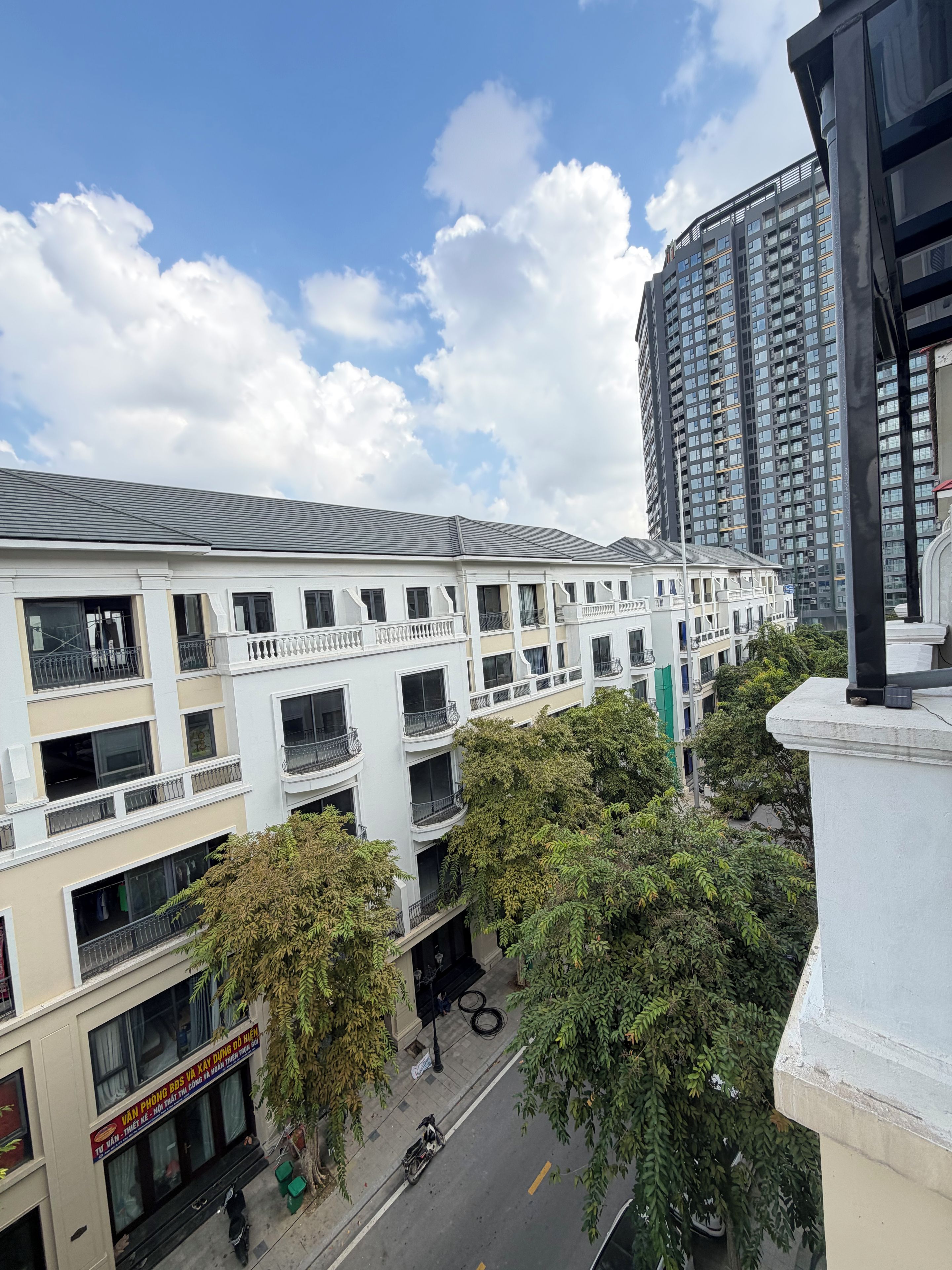 A multi-story building with balconies, a street in front, and a clear sky.