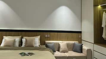 A modern hotel room with a large bed, a sofa, a small table, and a wardrobe.