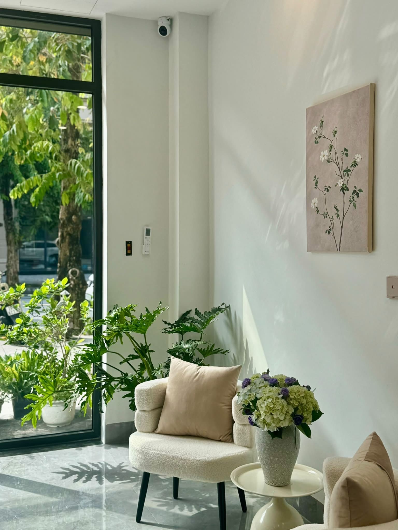 Un interior moderno con una zona de estar, un jarrón con flores y una obra de arte en la pared.