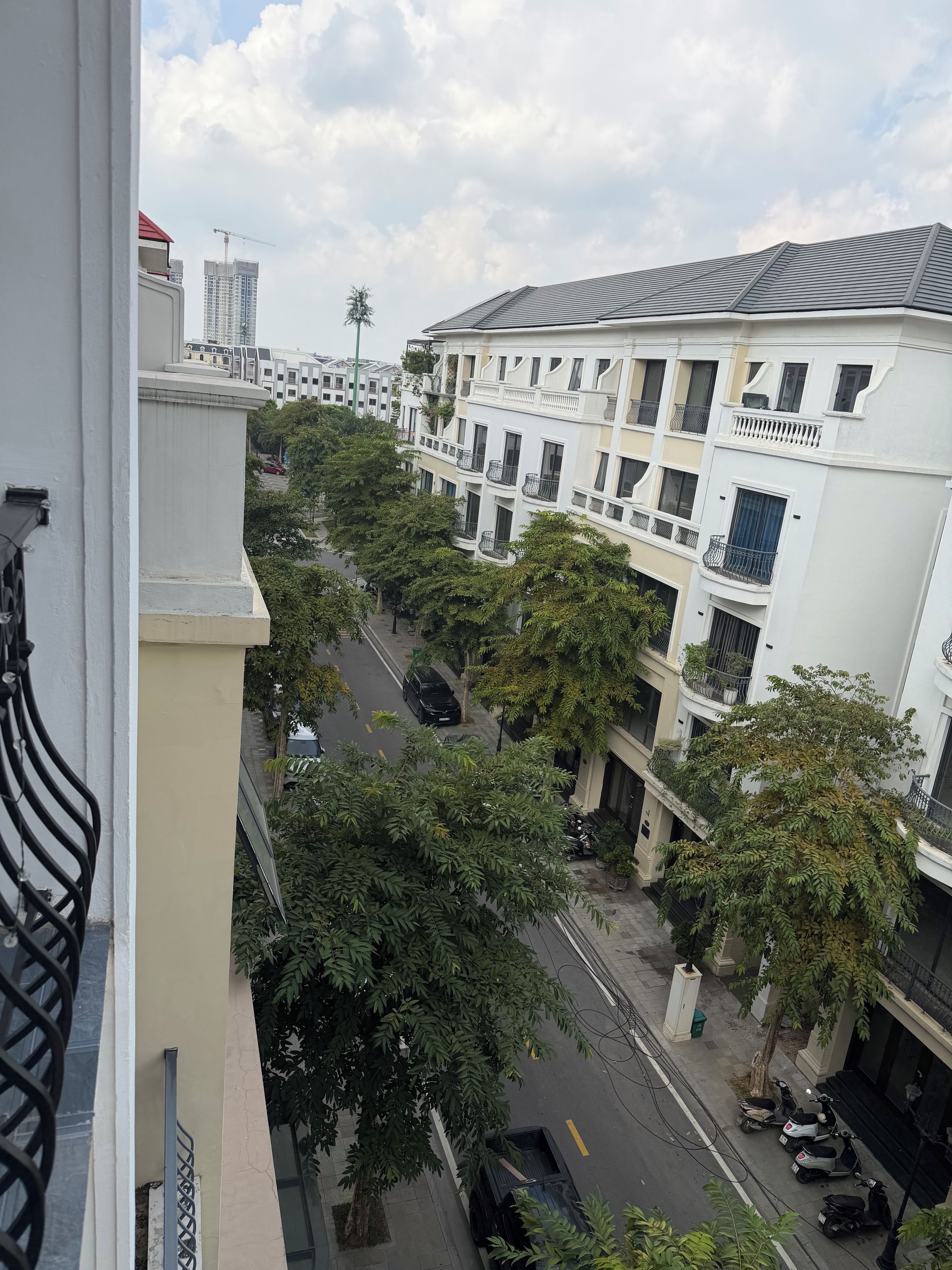 Een meerlaags woongebouw met balkons, een straatbeeld en een bouwkraan op de achtergrond.