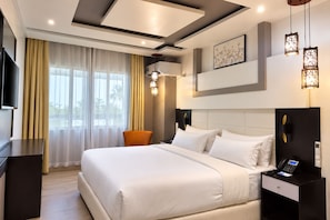 A modern hotel room with a large bed, a TV, a desk, and a chair. - Hotel Copacabana Beach Kribi  (Kribi)