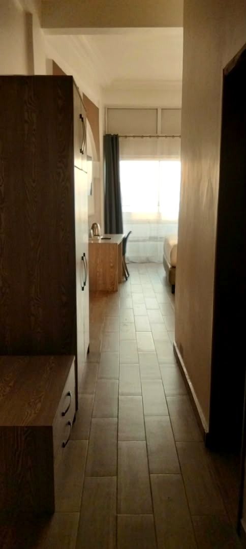 Ein Korridor mit einem Holzschrank, einem Essbereich mit Tisch und Stühlen sowie einem Fenster mit Vorhängen.