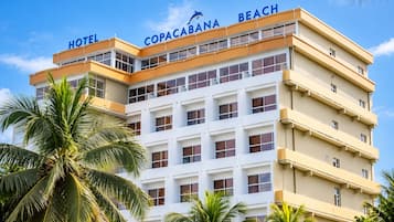 Un hotel de varios pisos con un letrero destacado que dice 'COPACABANA BEACH HOTEL' y balcones en cada planta.