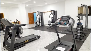 A gym with treadmills, weight machines, and a mirror. - Hotel Copacabana Beach Kribi  (Kribi)