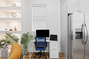 Una cocina moderna con refrigerador empotrado, encimera blanca y ventana con persianas.