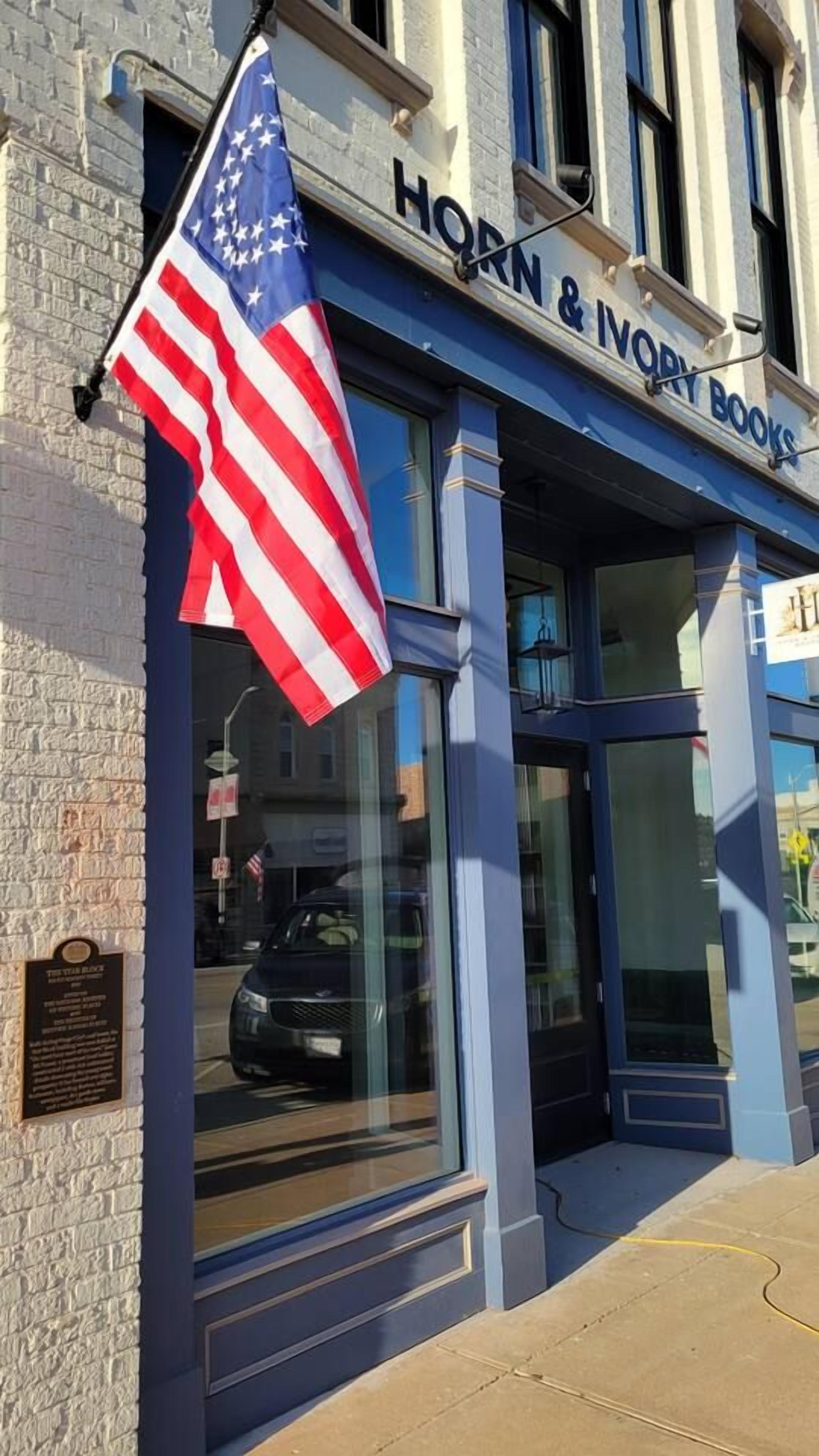 Een winkel met een bord waarop 'Horn & Ivory Books' staat en een Amerikaanse vlag.