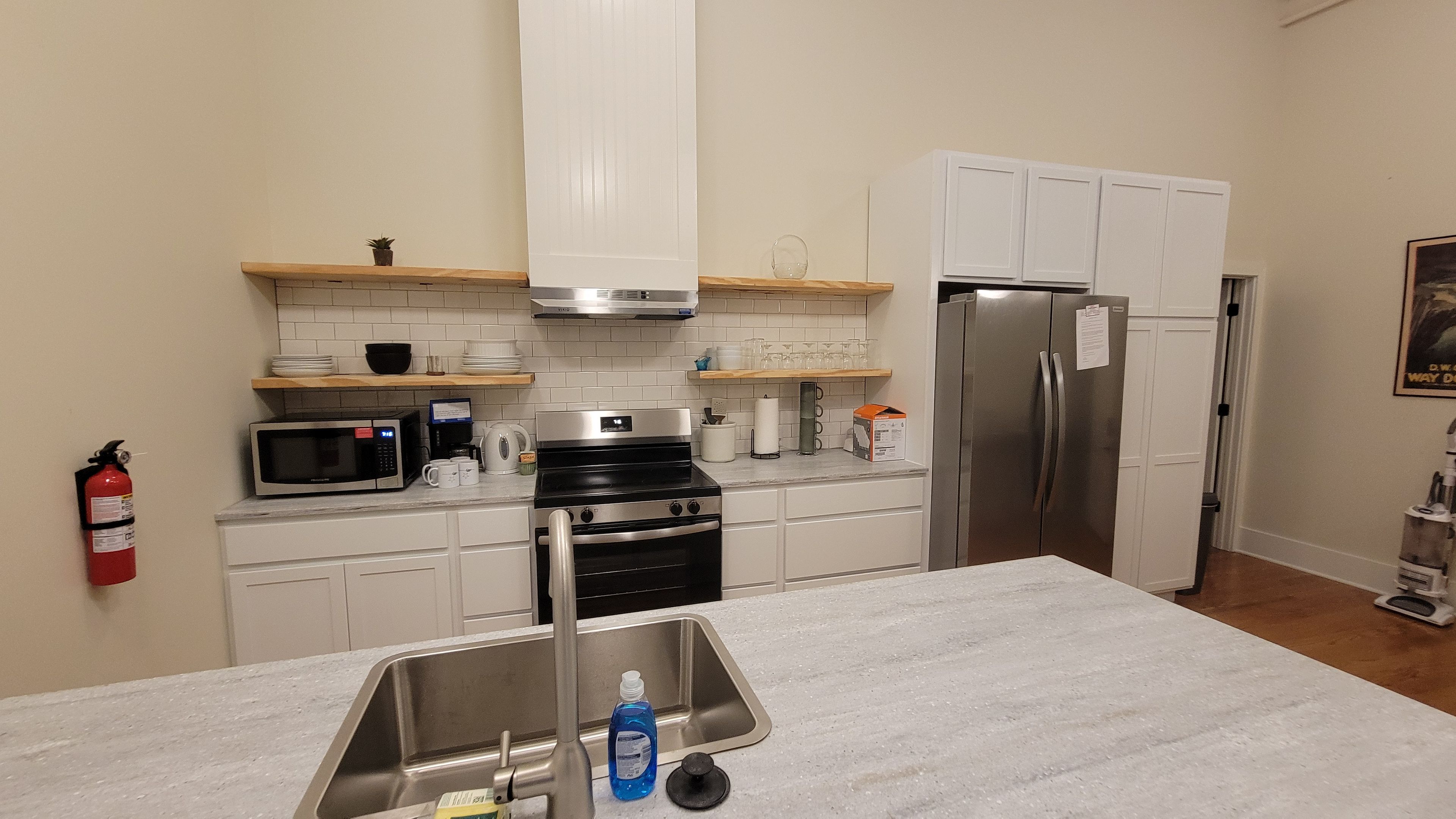 A modern kitchen with a stainless steel sink, a microwave, a stove, and a refrigerator.