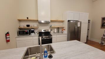 A modern kitchen with a stainless steel sink, a microwave, a stove, and a refrigerator.