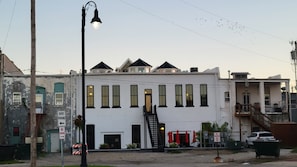 A white building with multiple windows and a black staircase leading to the entrance. - The Vaudeville Suite at The 1883 Guesthouse (Osage City)