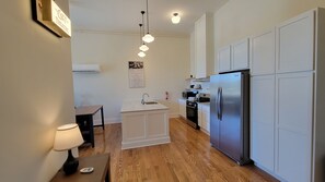 Una cocina moderna con refrigerador de acero inoxidable, armarios blancos y una isla central con pileta.