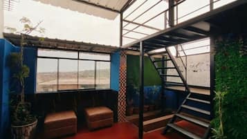 Une pièce avec de grandes fenêtres offrant une vue dégagée, un escalier et un plancher rouge.
