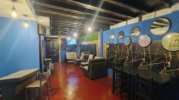 Un'area bar con posti a sedere e un bancone, una parete blu con specchi circolari e un pavimento rosso.